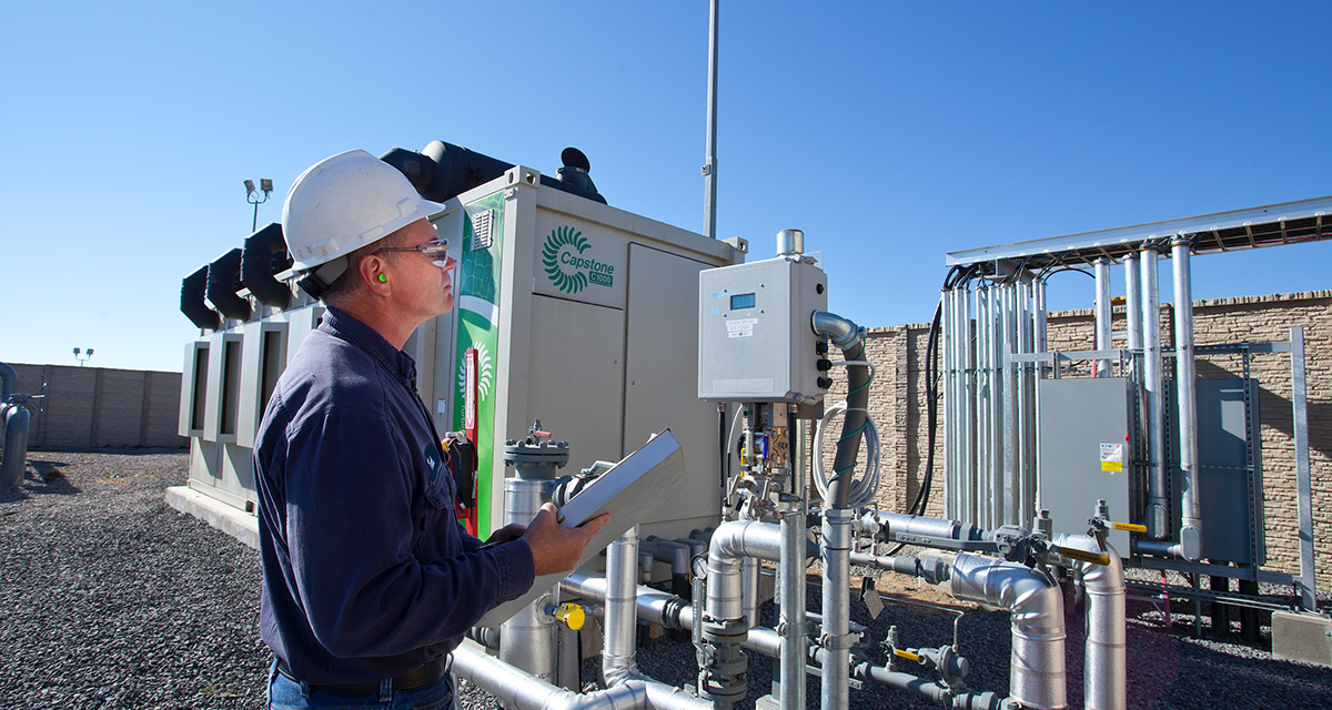 An employee is monitoring outdoor equipment gauges for clean, energy-efficient equipment.