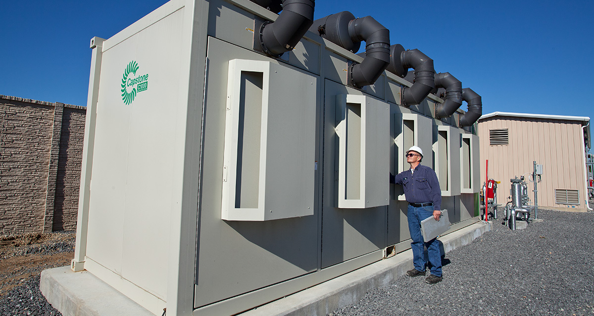 An employee is standing next to clean-energy efficient equipment.