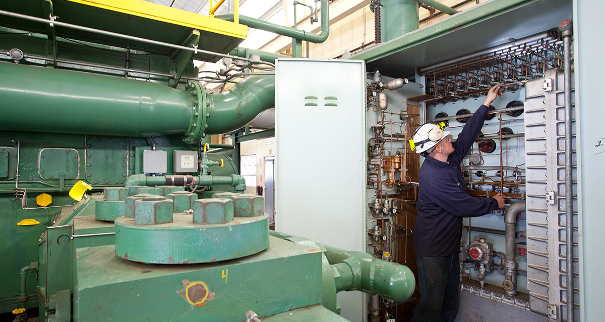 An Equitrans employee inspects small pipes and gauges in a designated equipment space.