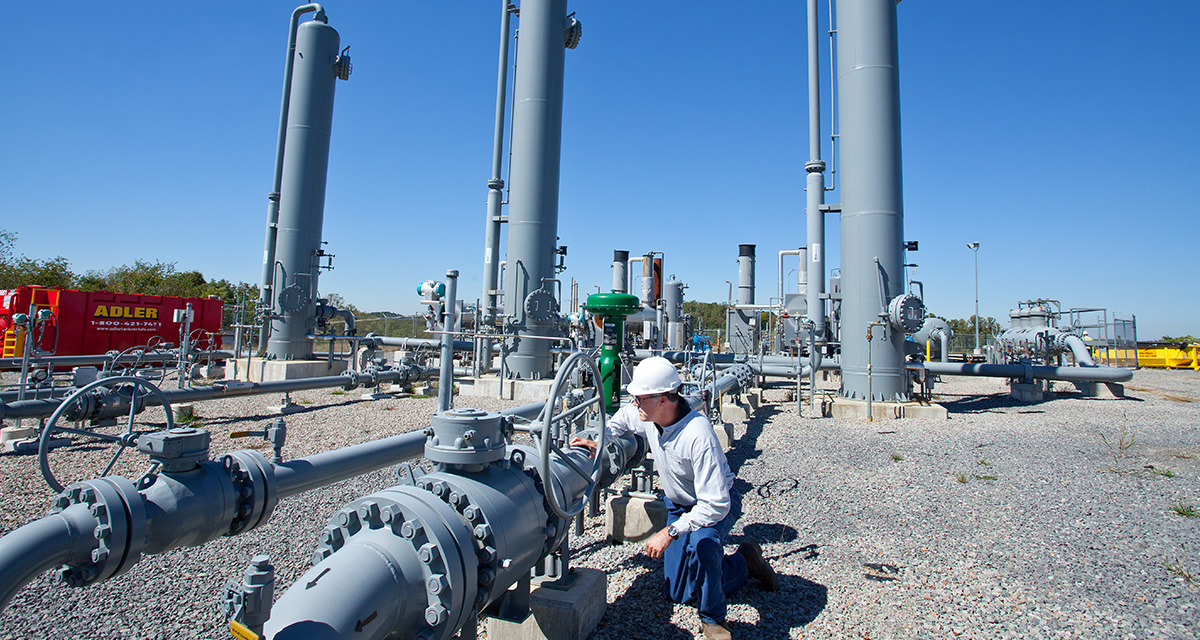 An Equitrans employee is wearing PPE inspecting a pipeline.